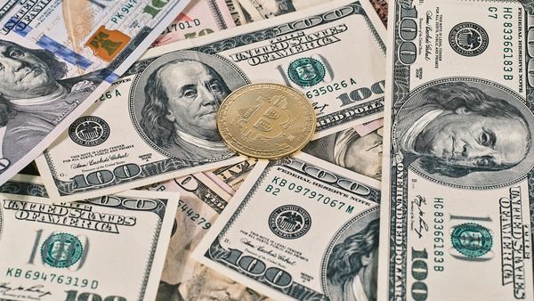 Gold crypto coin lying on a spread of US dollar banknotes