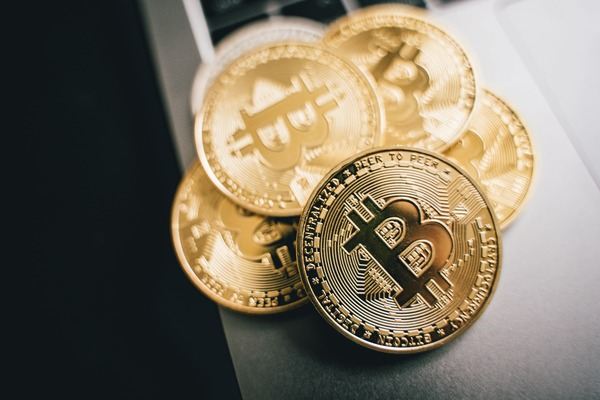 Pile of gold Bitcoin coins on a white surface