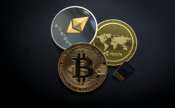 Bitcoin, Ethereum and Ripple coins with a memory card on a dark blue surface
