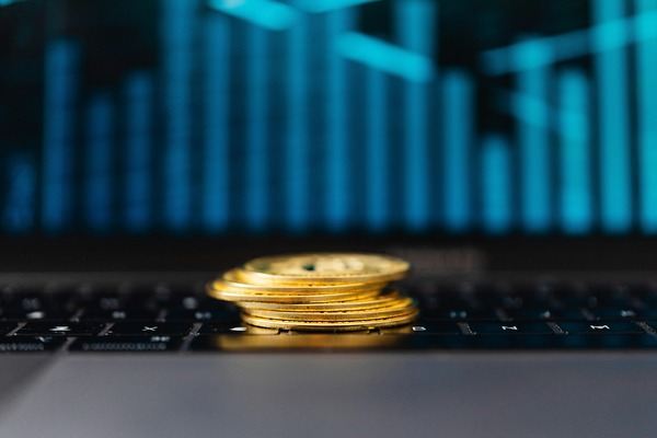 Stack of gold crypto coins on a laptop keyboard in blue light