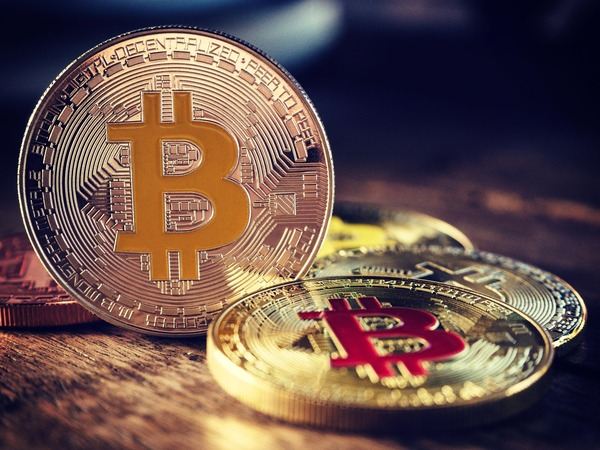 Gold Bitcoin coins on a wooden table in warm light