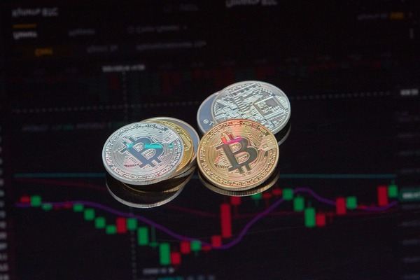 Stack of silver and gold crypto coins above a candlestick chart