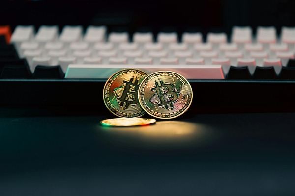 Two Bitcoin coins resting against a backlit keyboard