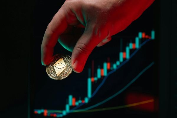Hand placing an Ethereum coin in front of a rising candlestick chart
