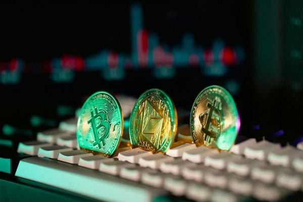 Three crypto coins on a keyboard lit by green and red neon light
