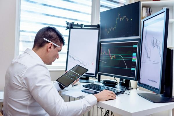 Analyst working with crypto charts on several monitors