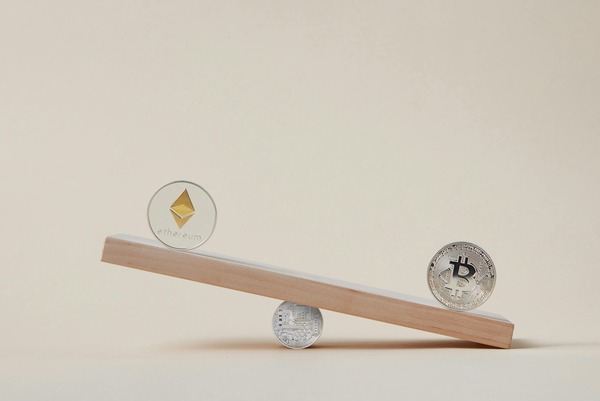 Ethereum and Bitcoin coins balancing on a wooden seesaw