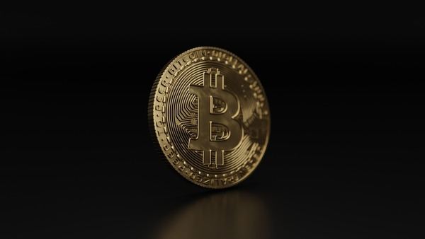 Single gold Bitcoin coin standing on a dark background
