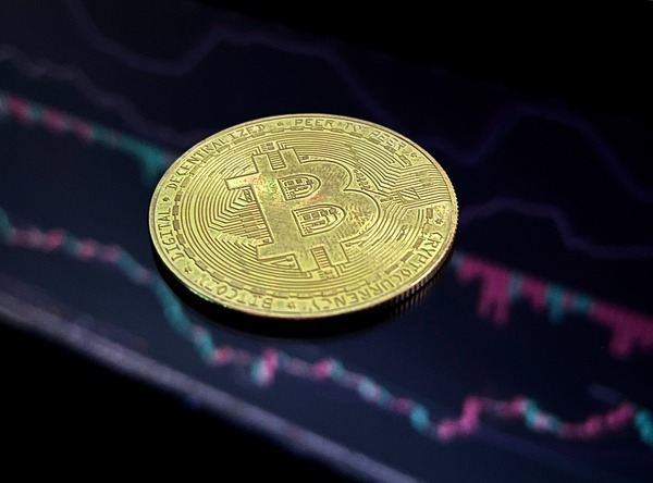 Gold Bitcoin coin lying on a dark price chart