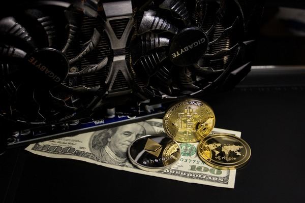 Graphics card with gold crypto coins resting on a 100 dollar bill