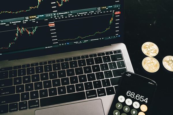 Laptop with a crypto chart, gold coins and a calculator on a dark desk