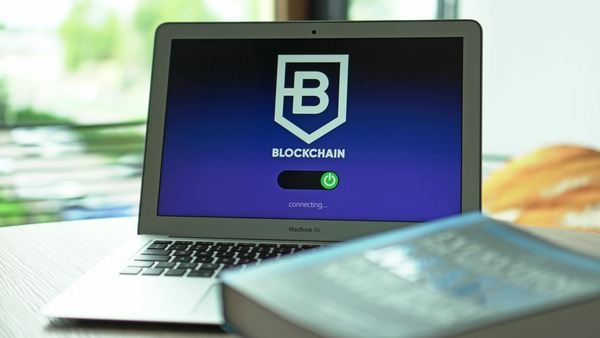 Laptop screen showing a blockchain app next to a book