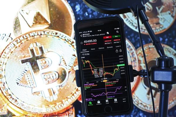 Smartphone with a trading chart in front of a large Bitcoin coin