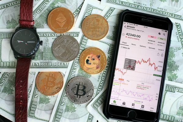 Smartphone with a crypto app among coins, a wristwatch and dollar bills