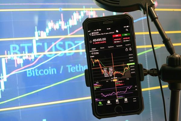 Smartphone showing a BTC/USDT trading chart in front of a Bitcoin Tether screen