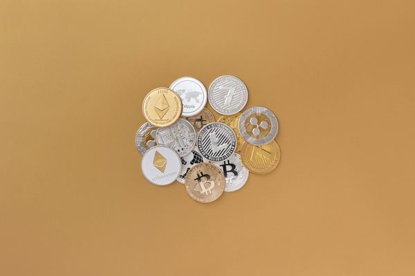 Assorted gold and silver cryptocurrency coins on a beige background