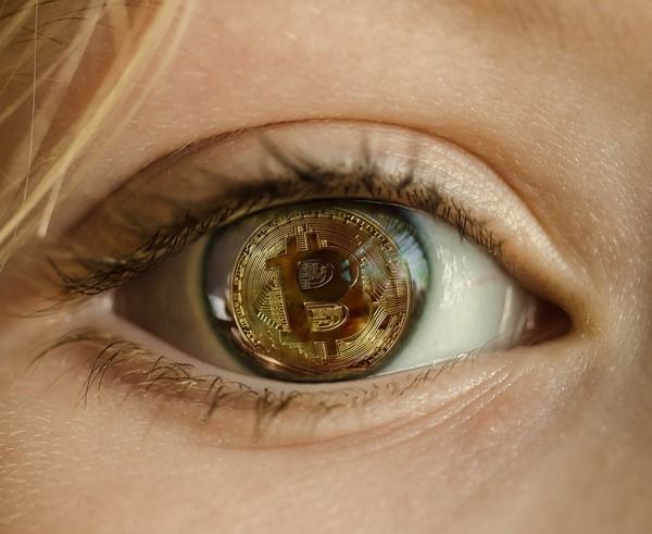 Close-up of a human eye reflecting a gold Bitcoin coin